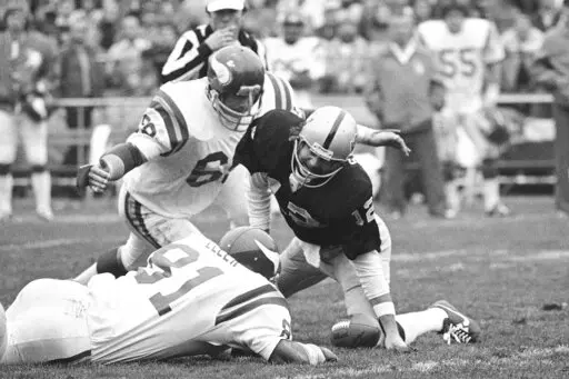 Oakland Raiders quarterback Ken Stabler (12) grimaces in pain as he recovers a fumble and goes down with twisted knee as Minnesota Vikings' Doug Sutherland (69) and Carl Eller (81) close in during the second quarter of an NFL football game in Oakland, Calif., Dec. 11, 1977. Sutherland, a member of the Purple People Eaters, has died. He was 73. The team released a statement Tuesday, April 5, 2022, without providing a cause. (AP Photo/Sal Veder, File)