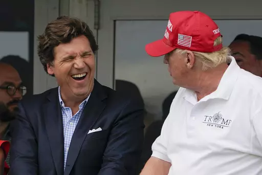 Tucker Carlson, left, and former President Donald Trump, right, react during the final round of the Bedminster Invitational LIV Golf tournament in Bedminster, N.J., July 31, 2022. A defamation lawsuit against Fox News is revealing blunt behind-the-scenes opinions by its top figures about Donald Trump, including a Tucker Carlson text message where he said “I hate him passionately.” Carlson's private conversation was revealed in court papers at virtually the same time as the former president w