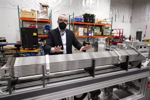 Chris Levesque, president and CEO of TerraPower, a company developing and building small nuclear reactors, displays a fuel assembly model, Thursday, Jan. 13, 2022, in Everett, Wash. The 5-foot model is about one-third actual length and would be vertical when in use, rather than horizontal. By cooling the reactor with liquid sodium, a metal that solidifies at well above room temperature, TerraPower says its relatively small, 345-megawatt plant will be safe and less expensive than conventional, wa