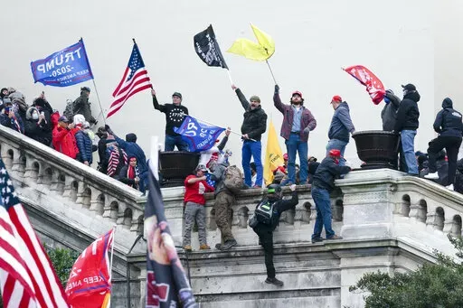 Rioters wave flags on the West Front of the U.S. Capitol in Washington on Jan. 6, 2021. As public trust in democratic institutions declines, conspiracy theories are filling the void. In some cases, that's leading believers to doubt even their own allies. (AP Photo/Jose Luis Magana, File)