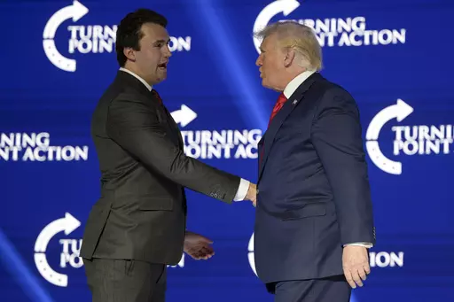 Former President Donald Trump, right, shakes hands with Turning Point CEO Charlie Kirk before speaking during the Turning Point USA Student Action Summit, July 23, 2022, in Tampa, Fla. The nonprofit rocketed to prominence by latching on to Trump’s 2016 campaign and has raised roughly a quarter-billion dollars since, much of it spent cultivating conservative influencers and hosting glitzy events. The organization also enriched Kirk and his allies, according to an Associated Press review of publ