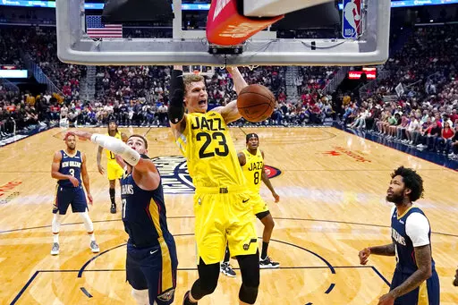 Utah Jazz forward Lauri Markkanen (23) slam dunks over New Orleans Pelicans center Jonas Valanciunas, left, and forward Brandon Ingram, right, in the first half of an NBA basketball game in New Orleans, Sunday, Oct. 23, 2022. (AP Photo/Gerald Herbert)