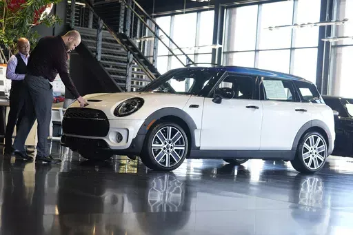 Salesmen examine an unsold 2024 Cooper Clubman S utility vehicle at a Mini dealership May 1, 2024, in Highlands Ranch, Colo. On Friday, May 31, 2024, the Commerce Department issues its report on consumer spending for April. (AP Photo/David Zalubowski, File)