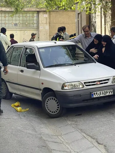 In this photo provided by Islamic Republic News Agency, IRNA, family members of Col. Hassan Sayyad Khodaei weep over his body at his car after being shot by two assailants in Tehran, Iran, Sunday, May 22, 2022. Hassan Sayyad Khodaei, a senior member of Iran's powerful Revolutionary Guard, was killed outside his home in Tehran on Sunday by unidentified gunmen on a motorbike, state TV reported. (IRNA via AP)