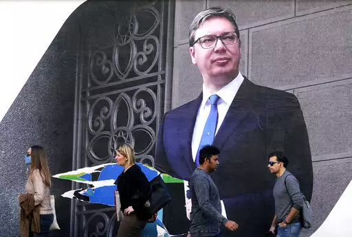 People walk by the pre-election billboard showing Current Serbian President and the Serbian Progressive Party leader Aleksandar Vucic in Belgrade, Serbia, Monday, March 28, 2022. Serbia's populist President Aleksandar Vucic, who has fostered close ties with Russia and refused to impose sanctions against Moscow over its invasion of Ukraine, is expected to extend his almost 10-year grip on power in the Balkan country at an election on Sunday. (AP Photo/Darko Vojinovic)