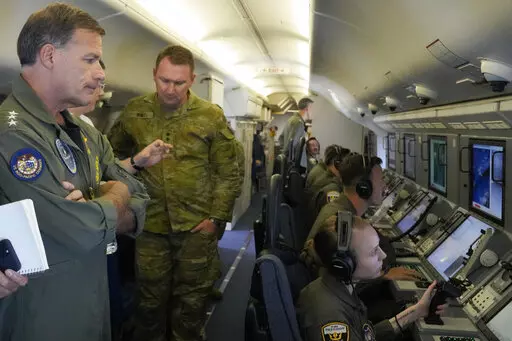 Admiral John C. Aquilino, left, Commander of the U.S. Indo-Pacific Command (INDOPACOM), looks at videos of Chinese structures and buildings on board a US P-8A Poseidon reconaisance plane flying at the Spratlys group of islands in the South China Sea on Sunday March 20, 2022. A U.S. Navy plane carrying a top American military commander was threatened repeatedly by radio on Sunday to leave the airspace over Chinese-occupied island garrisons in the disputed South China Sea, but the aircraft pressed