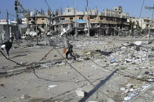 Palestinians walk through destruction by the Israeli bombardment in the Nusseirat refugee camp in Gaza Strip, Tuesday, Jan. 16, 2024. (AP Photo/Adel Hana)