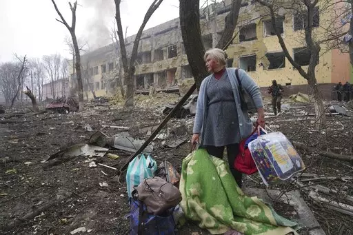 A woman walks outside a maternity hospital that was damaged by shelling in Mariupol, Ukraine, Wednesday, March 9, 2022. (AP Photo/Evgeniy Maloletka, File)