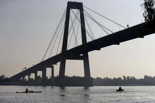 Two people canoe under the Hale Boggs Memorial Bridge in the Mississippi River in Luling, La., July 25, 2014. (AP Photo/Gerald Herbert, File)