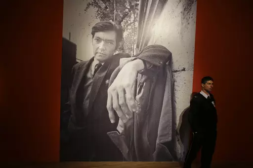 A security guard stands near a large photo of late writer Julio Cortazar at an exhibit marking the 100-year anniversary of his birth at the National Museum of Fine Arts in Buenos Aires, Argentina, Aug. 26, 2014. A bundle of 60-year-old pages of Cortazar´s writings was sold at auction on Thursday, October 12, 2023, by the Zorrilla de Montevideo auction house. (AP Photo/Victor R. Caivano, File)