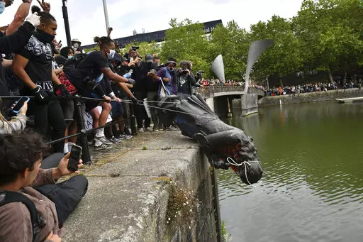 Protesters throw a statue of Edward Colston into the Bristol harbour during a Black Lives Matter protest rally, Bristol, England, June 7, 2020. Four anti-racism demonstrators were cleared Wednesday Jan. 5, 2022, of criminal damage in the toppling of a statue of a 17th century slave trader during a Black Lives Matter protest in southwestern England 18 months ago. (Ben Birchall/PA via AP, File)