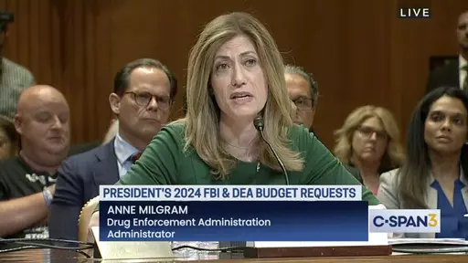In this image from video provided by C-SPAN, U.S. Drug Enforcement Administration Administrator Anne Milgram speaks during a hearing before the Senate Appropriations Subcommittee on Commerce, Justice, and Science in Washington on May 10, 2023. At center left behind Milgram is Louis Milione. After temporarily leaving the DEA in 2017, like dozens of colleagues in the agency's powerful-but-little-known Office of Diversion Control, Milione immediately went to work as a consultant for some of the sam