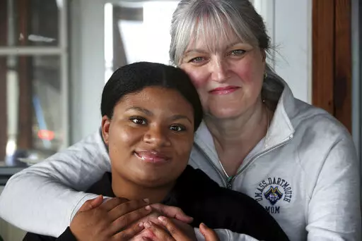 Deanna Cook, left, poses for a photograph with her mother Colleen at their home in Malden, Mass., Tuesday, March 15, 2022. A bill aimed at banning race-based discrimination targeting hair texture and hairstyles was unanimously approved Thursday, March 17, 2022 by the Massachusetts House. The issue came to light when the parents of then-15-year-old Black girls, Deanna and Mya Cook, said their twin daughters were punished for wearing extensions, while white students hadn't been punished for violat