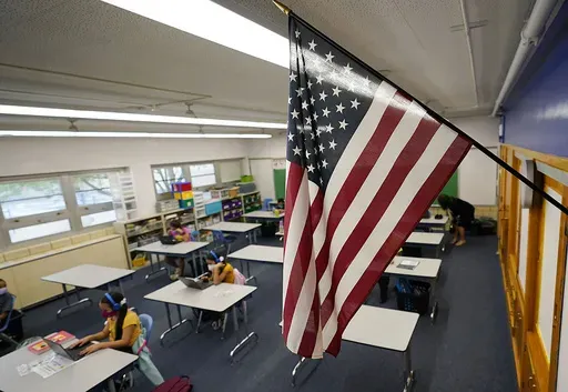 An American flag hangs in a classroom as students work on laptops in Newlon Elementary School, in Denver, Aug. 25, 2020. (AP Photo/David Zalubowski, File)
