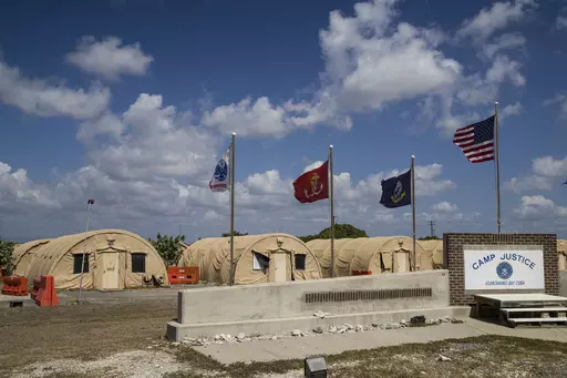 In this photo reviewed by U.S. military officials, flags fly in front of the tents of Camp Justice in Guantanamo Bay Naval Base, Cuba, on April 18, 2019. For the first time since the facility in Cuba opened in 2002, a U.S. president had allowed a United Nations independent investigator, Fionnuala Ní Aoláin, to visit. (AP Photo/Alex Brandon, File)