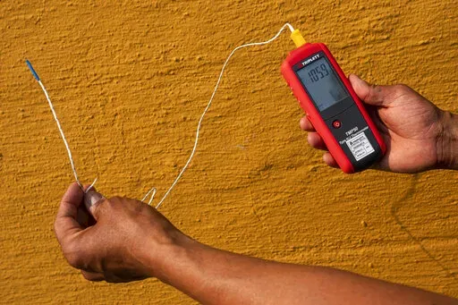 Vivek Shandas, a professor of climate adaptation at Portland State University, takes a temperature reading of almost 106 degrees in downtown Portland, Ore., on Aug. 12, 2021. On Thursday, Jan. 13, 2022, NASA and the National Oceanic and Atmospheric Administration released measurements showing 2021 was the sixth hottest year on record globally, part of a long-term warming trend. (AP Photo/Nathan Howard, File)