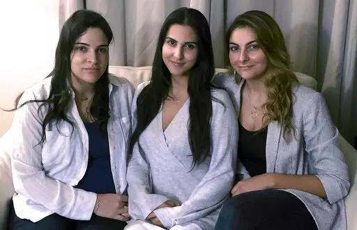 FILE — Three of Amer Fakhoury's four daughters, from left, Guila, Macy, and Zoya Fakhoury, gather Nov. 5, 2019, in Salem, N.H. Amer Fakhoury was a Lebanese American restaurant owner who made his first trip back to Lebanon in 2019 in nearly 20 years to see family. In Lebanon he was accused of torturing and killing inmates at a former prison where his family says he had worked as a clerk. Fakhoury was released in March 2020 and died that August from lymphoma. The Fakhourys are trying to sue Leba