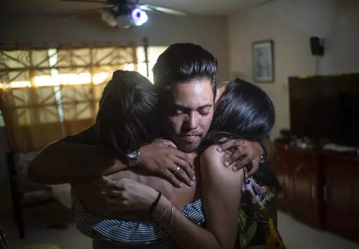 Marcos Marzo hugs two of his friends who came to say goodbye upon receiving the news that he had obtained a permit to travel to the United States, in Havana, Cuba, Wednesday, Jan 25, 2023. Now in the U.S., his dream is to do a master’s degree at the Massachusetts Institute of Technology and work as an engineer, which he says is his passion. (AP Photo/Ramon Espinosa)