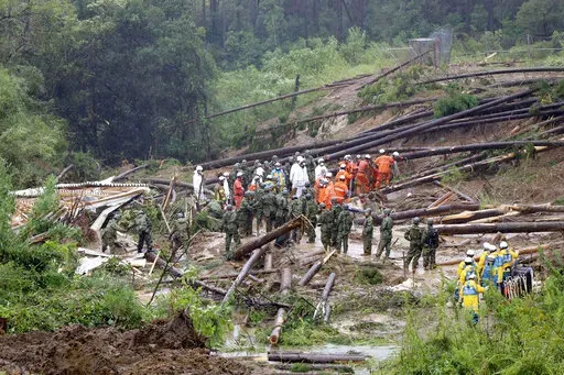 Rescuers conduct a search operation at the site of a landslide in Mimata, Miyazaki Prefecture, southern Japan, Monday Sept. 19, 2022. Powerful Typhoon Nanmadol slammed ashore in southern Japan on Sunday as it pounded the region with strong winds and heavy rain, causing blackouts, paralyzing ground and air transportation and prompting the evacuation of thousands of people. (Kyodo News via AP)