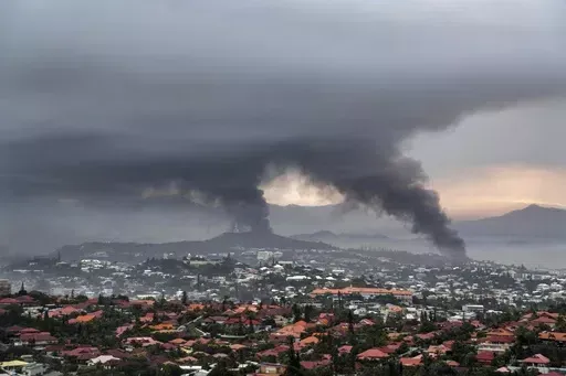 Smoke rises during protests in Noumea, New Caledonia, Wednesday May 15, 2024. The French Pacific territory of New Caledonia is shortening its overnight curfew and reopening its international airport that was closed to commercial flights for more than a month because of deadly violence. The archipelago's high commissioner said Sunday, June 16, 2024 the La Tontouta airport that links New Caledonia’s capital, Nouméa, to Sydney, Tokyo and other Pacific hubs will reopen Monday. (AP Photo/Nicolas J