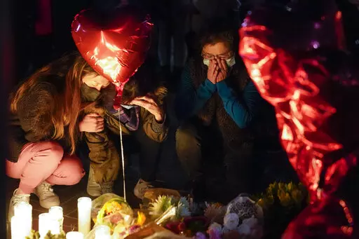 Women pause at a memorial at a vigil honoring the victims of a shooting at the Star Ballroom Dance Studio on Monday, Jan. 23, 2023, in Monterey Park, Calif. A gunman killed multiple people late Saturday amid Lunar New Years celebrations in the predominantly Asian American community. (AP Photo/Ashley Landis)