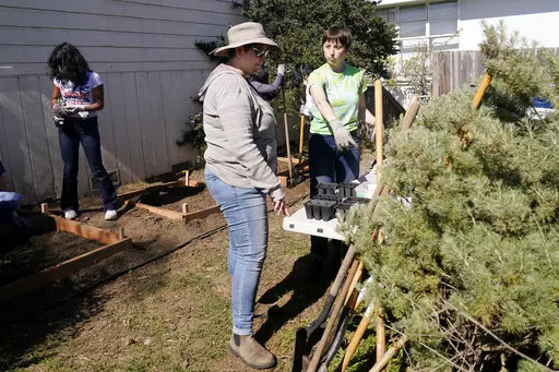 Food Justice Club leader and Lick-Wilmerding High School senior Lucy, right, talks with junior and senior class Dean and Food Justice club moderator Kindra Briggs as students work during a garden maintenance session at the high school in San Francisco, Wednesday, March 9, 2022. (AP Photo/Jeff Chiu)