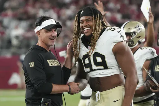 New Orleans Saints head coach Dennis Allen laughs with defensive end Chase Young (99) in the second half of a preseason NFL football game against the Arizona Cardinals, Saturday, Aug. 10, 2024, in Glendale, Ariz. (AP Photo/Rick Scuteri)