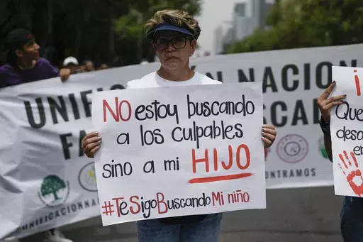 Maria del Carmen Ayala Vargas, who said her son Ivan Pasrtana Ayala disappeared in 2021, attends the annual National March of Searching Mothers, held every Mother's Day in Mexico City, Friday, May 10, 2024. Her sign reads in Spanish, "I'm not looking for those to blame, but for my son." (AP Photo/Marco Ugarte)