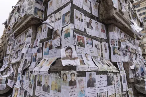 Portraits of missing people whose families say they were taken by the Assad regime are plastered across a monument in Damascus, Syria, Saturday, Dec. 28, 2024 (AP Photo/Mosa'ab Elshamy)