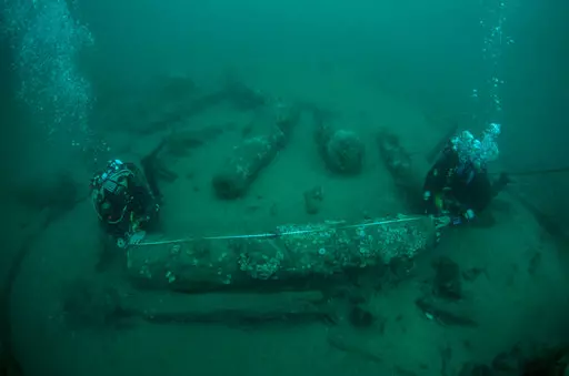 In this undated photo provided by Norfolk Historic Shipwrecks, Julian And Lincoln Barnwell measure the cannon found on the HMS Gloucester in 2007. Excavators and historians are telling the world about the wreck of a royal warship that sank in 1682 while carrying the future king James Stuart. The HMS Gloucester ran aground while navigating sandbanks off the town of Great Yarmouth on the eastern English coast. The wreck of the Gloucester was found in 2007 by brothers Julian and Lincoln Barnwell an
