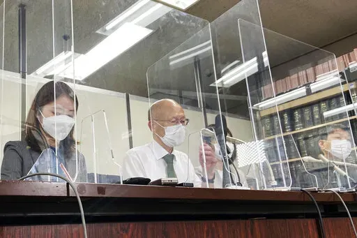 Lawyer Kenichi Ido, second left, sitting among other lawyers representing plaintiffs who were children in Fukushima at the time of the 2011 nuclear disaster and later developed thyroid cancer, speaks during a news conference after a trial in Tokyo, Thursday, May 26, 2022. A Tokyo court began hearing a case Thursday seeking nearly $5 million in damages for six people who lived as children in Fukushima and developed thyroid cancer after its 2011 nuclear disaster. (AP Photo/Mari Yamaguchi)