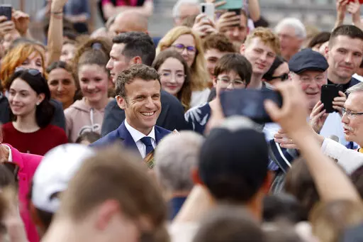 Current French President and centrist presidential candidate for reelection Emmanuel Macron, center, speaks with locals residents about security, in Chatenois, eastern France, Tuesday, April 12, 2022 . Macron, with strong pro-European views, and far-right candidate Marine Le Pen, an anti-immigration nationalist, are facing each other in the presidential runoff on April 24. (AP Photo/Jean-Francois Badias)