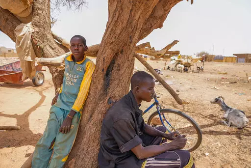 People lean on a tree in Djibo, Burkina Faso, Thursday May 26, 2022. African leaders have gathered for a summit in Malabo, Equatorial Guinea, to address growing humanitarian needs on the continent, which is also facing increased violent extremism, climate change challenges and a run of military coups. Leaders on Friday called for increased mobilization to resolve a humanitarian crisis that has left millions displaced and more than 280 million suffering from malnourishment. (AP Photo/Sam Mednick)