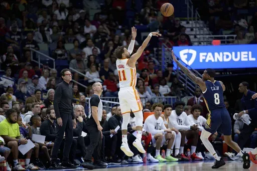 Atlanta Hawks guard Trae Young (11) shoots over New Orleans Pelicans forward Jamal Cain (8) as Atlanta Hawks head coach Quin Snyder watches during the first half of an NBA basketball game in New Orleans, Sunday, Nov. 3, 2024. (AP Photo/Matthew Hinton)