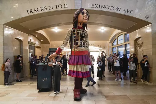 A 12-foot puppet of a 10-year-old Syrian refuge named Little Amal walks around Grand Central Station in New York, on Sept. 15, 2022. Little Amal will journey across the United States this fall, visiting key places in America’s history in an attempt to raise awareness about immigration and migration.(AP Photo/Seth Wenig, File)