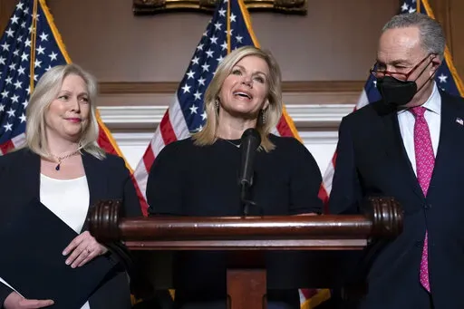 Former Fox News anchor Gretchen Carlson, center, celebrates with Sen. Kirsten Gillibrand, D-N.Y., left, and Senate Majority Leader Chuck Schumer, D-N.Y., after Congress gave final approval to legislation guaranteeing that people who experience sexual harassment at work can seek recourse in the courts, during a news conference at the Capitol in Washington, Thursday, Feb. 10, 2022. Since her 2016 sexual harassment lawsuit against then Fox News Chairman and CEO Roger Ailes, Carlson has worked to ba