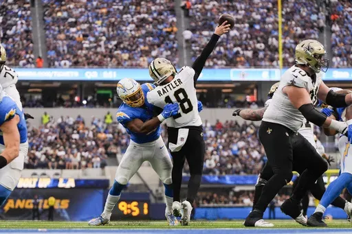New Orleans Saints quarterback Spencer Rattler (18) is hit by Los Angeles Chargers linebacker Daiyan Henley (0) as he releases the ball in the second half of an NFL football game in Inglewood, Calif., Sunday, Oct. 27, 2024. (AP Photo/Mark J. Terrill)