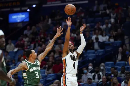 New Orleans Pelicans guard Devonte' Graham (4) shoots over Milwaukee Bucks guard George Hill (3) in the first half of an NBA basketball game in New Orleans, Friday, Dec. 17, 2021. (AP Photo/Gerald Herbert)