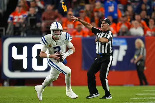 The referee throws a flag as Indianapolis Colts quarterback Matt Ryan (2) runs during the first half of an NFL football game against the Denver Broncos, Thursday, Oct. 6, 2022, in Denver. (AP Photo/Jack Dempsey)