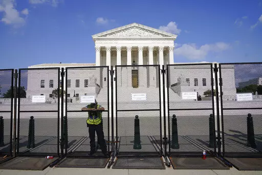 An officer rests on a fence outside the Supreme Court in Washington, Friday, June 24, 2022. The Supreme Court has ended constitutional protections for abortion that had been in place nearly 50 years, a decision by its conservative majority to overturn the court's landmark abortion cases. (AP Photo/Jacquelyn Martin)
