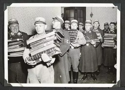 This photo released by Yad Vashem, World Holocaust Remembrance Center, shows German Nazis carry Jewish books, presumably for burning, during Kristallnacht intake most likely in the town of Fuerth, Germany on Nov. 10, 1938. The photos were taken by Nazi photographers during the pogrom in the city of Nuremberg and the nearby town of Fuerth. They wound up in the possession of a Jewish American serviceman who served in Germany during World War II. His descendants,donated the album to Yad Vashem. (Ya
