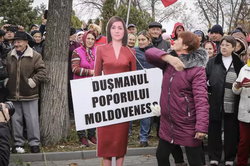 A woman slaps a cardboard cutout of Moldova's pro-western President Maia Sandu, with writing reading "Enemy of the Moldovan People", during a protest initiated by the populist Shor Party, in Chisinau, Moldova, Sunday, Nov. 13, 2022. Shor, a fugitive Moldovan oligarch and opposition leader has been sentenced in absentia to 15 years in jail for his alleged role in a one-billion-dollar bank fraud case, Moldova's President said. The Court of Appeal in the capital, Chisinau, sentenced Ilan Shor, who 