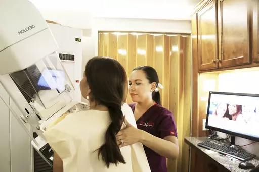 Mammographer Alma Garcia, right, demonstrates the process of a mammogram on marketing liaison Dalilah Garcia of the Neighbors Emergency Center in Brownsville, Texas, on Monday, Sep. 18, 2017, inside a Mammos on the Move (MOM) mobile mammogram trailer. According to a draft recommendation from a government task force released on Tuesday, May 9, 2023, women should start getting every-other-year mammograms at age 40 instead of waiting until 50. Tuesday’s update – if the draft proposal is finaliz