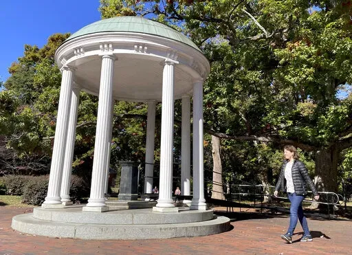 A student walks by the Old Well at the University of North Carolina at Chapel Hill, a rotunda and campus landmark at the southern end of McCorkle Place, on Monday, Oct. 24, 2022. A Confederate statue known as Silent Sam statue once stood in the plaza before it was toppled by protesters in 2018. (AP Photo/Hannah Schoenbaum)