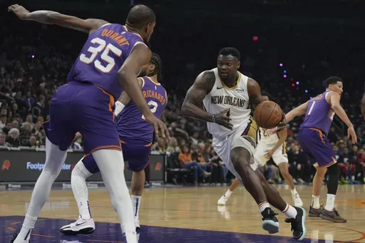 New Orleans Pelicans forward Zion Williamson (1) drives on Phoenix Suns center Nick Richards (2) and forward Kevin Durant during the first half of an NBA basketball game, Thursday, Feb. 27, 2025, in Phoenix. (AP Photo/Rick Scuteri)
