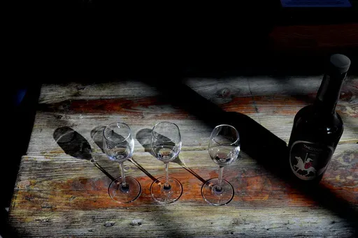 A bottle of Cyprus' famous Commandaria wine sits next to three glasses at the Karseras Winery in the mountain village of Doros on Friday, Feb. 21, 2025. (AP Photo/Petros Karadjias)
