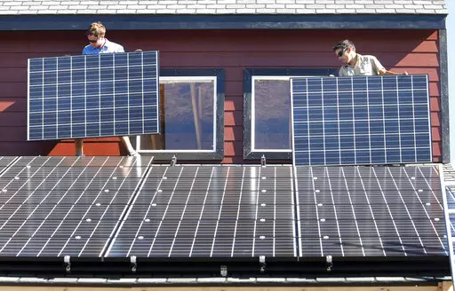 Workers install two of 105 solar panels on the roof of a barn Thursday, Aug. 27, 2009, north of Hesperus, Colo. The Inflation Reduction Act includes tax credits and rebates for homeowners who make energy-saving updates to their homes. Tax credits are available now for updates like new windows, doors, air conditioners, insulation and solar panels, while larger rebates for energy-saving and electrification updates are expected to become available later this year or early next year. (AP Photo/Jerry