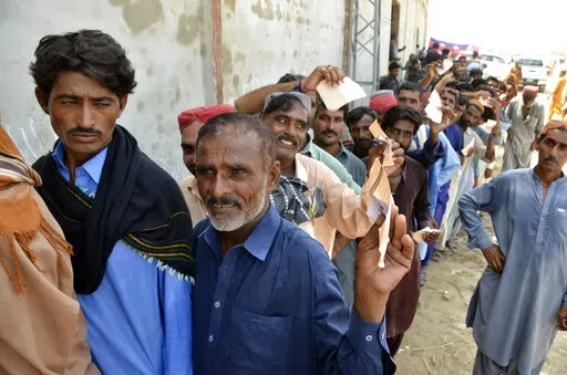 Displaced families, who fled their flood-hit homes, line up to get relief aid in Jaffarabad, a district of Baluchistan province, Pakistan, Wednesday, Sept. 21, 2022. Devastating floods in Pakistan's worst-hit province have killed 10 more people in the past day, including four children, officials said Wednesday as the U.N. children's agency renewed its appeal for $39 million to help the most vulnerable flood victims. (AP Photo/Zahid Hussain)