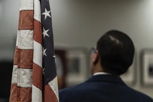 Winston Leiva, community education programs manager at the Coalition for Humane Immigrant Rights, stands next to a U.S. flag while giving a bilingual workshop for immigrants who want to stay in the United States, in Los Angeles, Wednesday, Dec. 4, 2024. (AP Photo/Jae C. Hong)