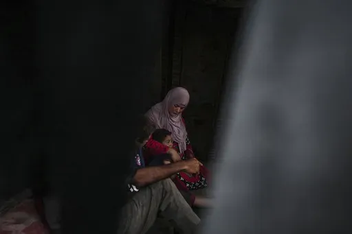 Basima al-Batsh sits with her family ahead of the Eid al-Adha holiday in Deir al Balah, Gaza Strip, Tuesday, June 11, 2024. They were displaced from their home by the war between Israel and Hamas. (AP Photo/Abdel Kareem Hana)